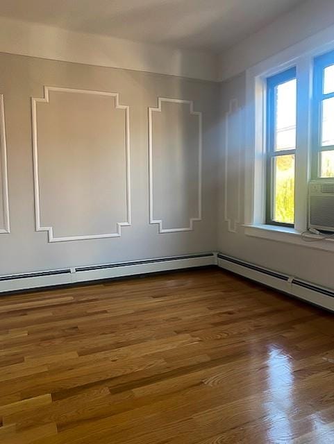 empty room with baseboard heating and dark wood-type flooring