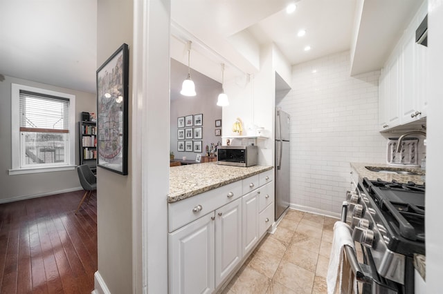 kitchen with stainless steel appliances, white cabinetry, decorative light fixtures, and light stone countertops