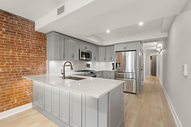 1030 Hudson St Unit 1, Hoboken, NJ 07030 - kitchen with stainless steel appliances, gray cabinetry, a sink, a peninsula, and baseboards
