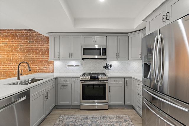 1030 Hudson St Unit 1, Hoboken, NJ 07030 - kitchen with stainless steel appliances, gray cabinetry, a sink, light countertops, and decorative backsplash