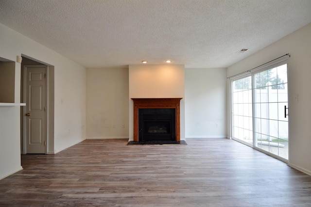 unfurnished living room featuring wood finished floors, a textured ceiling, visible vents, recessed lighting, and a fireplace