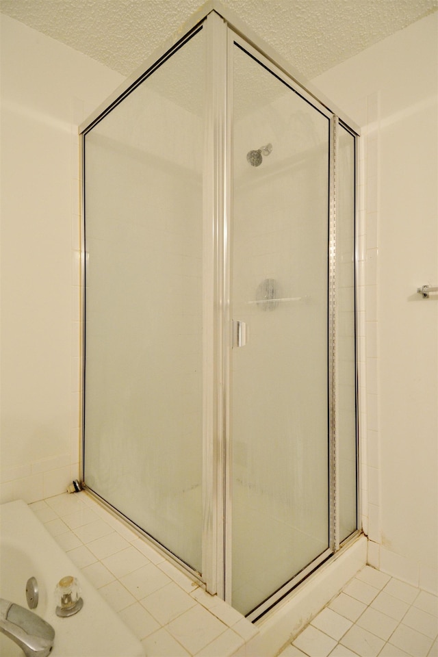 full bathroom with a stall shower, a jetted tub, tile patterned floors, and a textured ceiling
