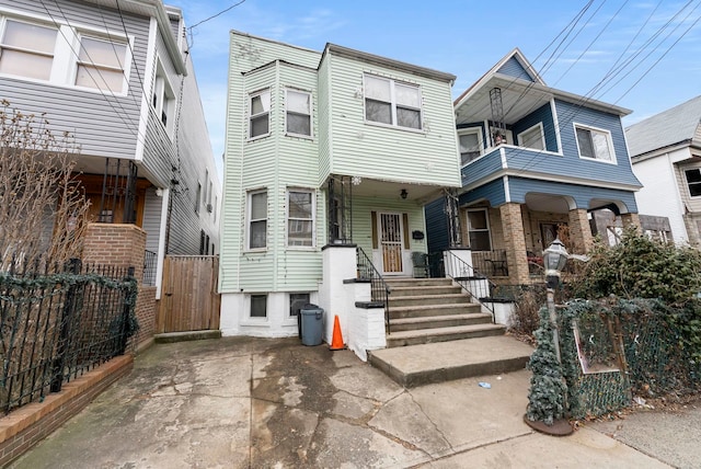 view of property with a porch, a balcony, and fence