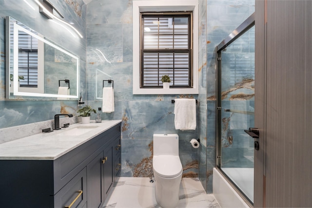 full bathroom with toilet, vanity, tile walls, marble finish floor, and combined bath / shower with glass door