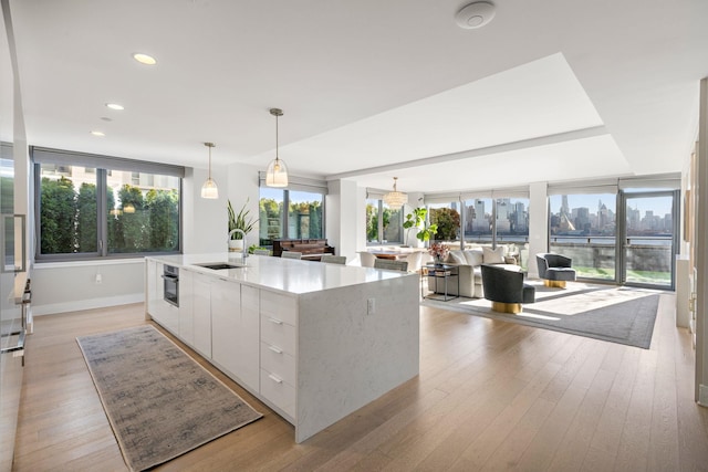 kitchen featuring white cabinets, light wood-type flooring, hanging light fixtures, and a spacious island