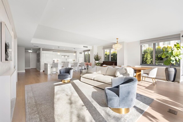 living room with an inviting chandelier, expansive windows, light wood-type flooring, a fireplace, and beamed ceiling