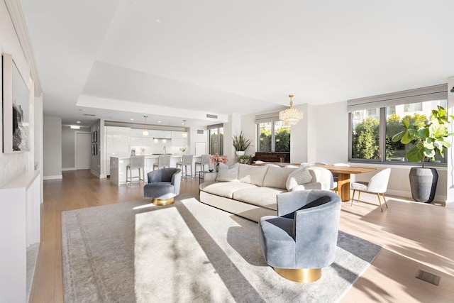 living area featuring a chandelier, wood finished floors, visible vents, and baseboards