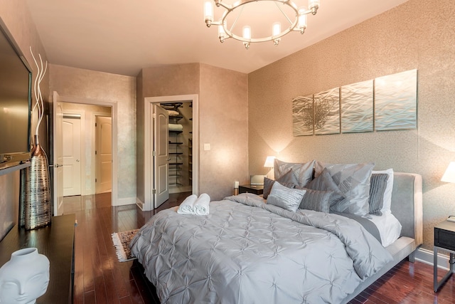 bedroom featuring dark wood-type flooring, a closet, a spacious closet, and a notable chandelier