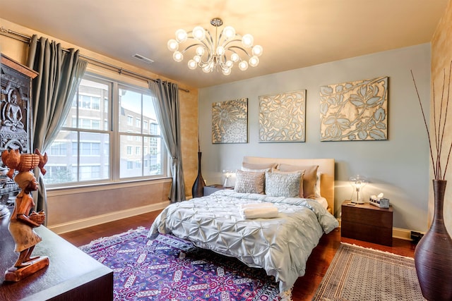 bedroom with dark hardwood / wood-style floors and an inviting chandelier