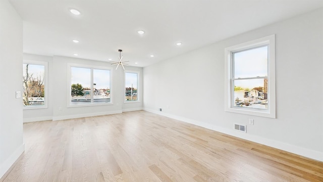 unfurnished room with an inviting chandelier and light hardwood / wood-style flooring