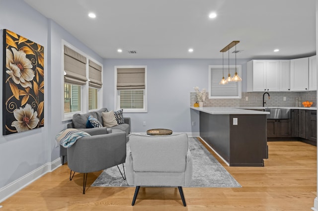 living room featuring sink and light hardwood / wood-style flooring