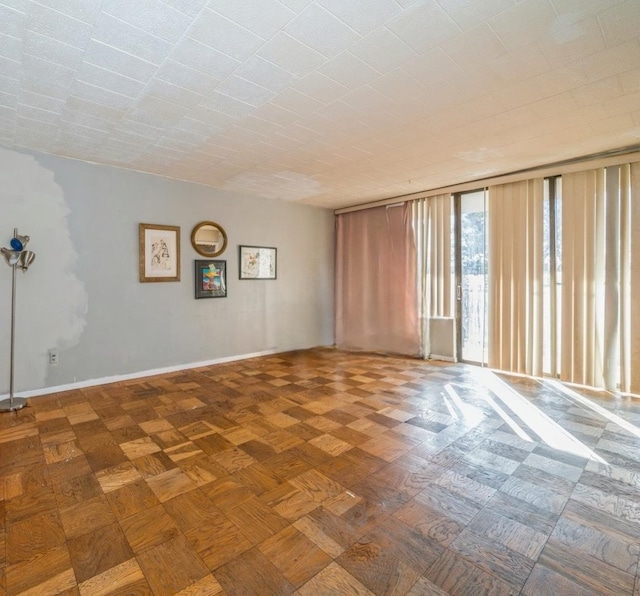 unfurnished room with parquet floors and a wall of windows