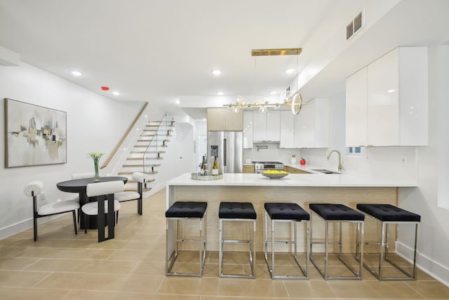 kitchen with a breakfast bar, a peninsula, appliances with stainless steel finishes, and a sink