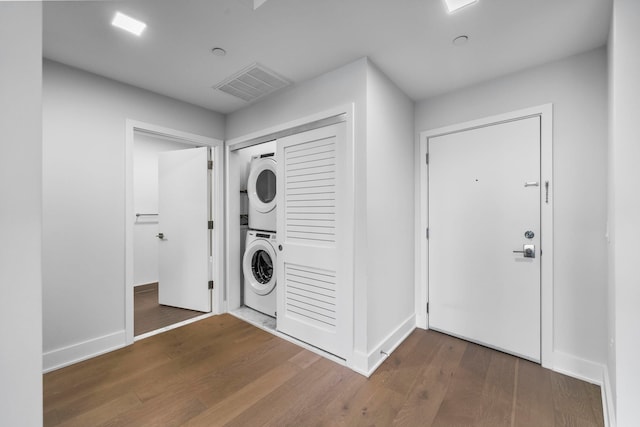 washroom with laundry area, baseboards, visible vents, stacked washer and clothes dryer, and wood finished floors