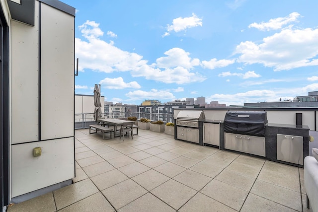 view of patio with grilling area, an outdoor kitchen, a city view, and outdoor dining space