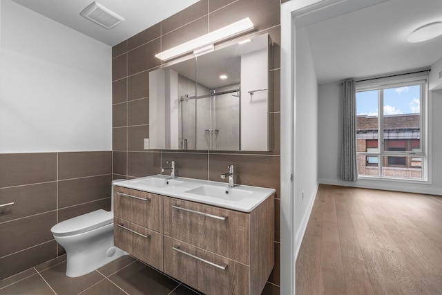 bathroom with visible vents, a sink, tile walls, and a shower stall