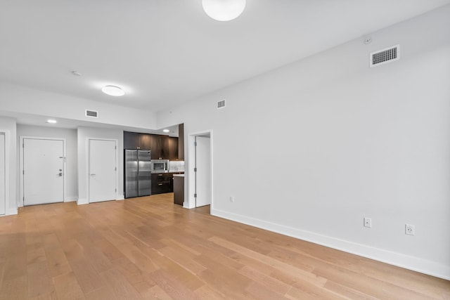 unfurnished living room with light wood-style flooring, visible vents, and baseboards