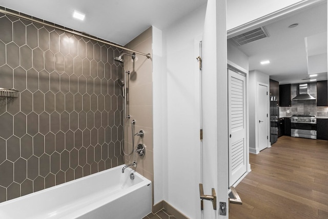 full bath with tasteful backsplash, baseboards, visible vents, wood finished floors, and  shower combination