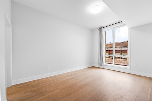 empty room featuring light wood finished floors and baseboards