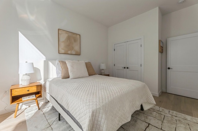 bedroom with light hardwood / wood-style floors and a closet