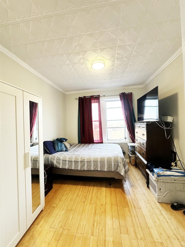 bedroom featuring crown molding, an ornate ceiling, and light wood-style floors