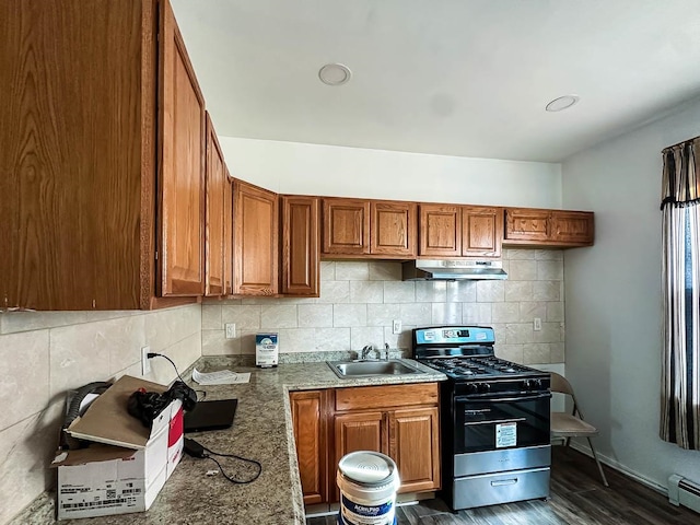 kitchen with light stone counters, backsplash, dark hardwood / wood-style floors, stainless steel range with gas cooktop, and sink