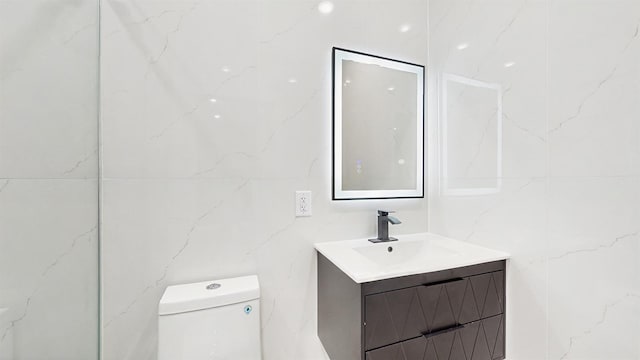 bathroom featuring toilet, vanity, and tile walls