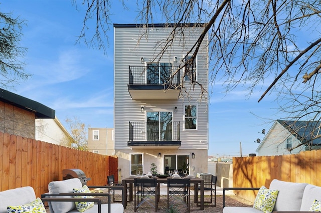 back of property with outdoor dining area, a fenced backyard, a balcony, and stucco siding