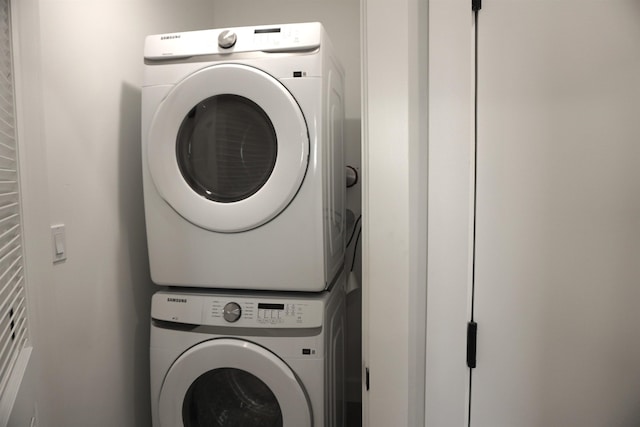 washroom with stacked washing maching and dryer and laundry area