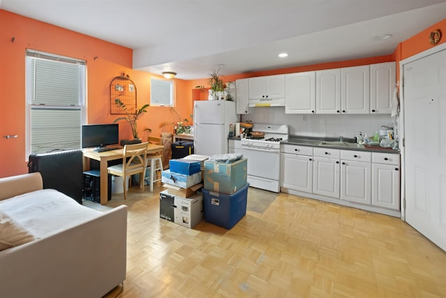 kitchen featuring white appliances, white cabinetry, under cabinet range hood, and recessed lighting