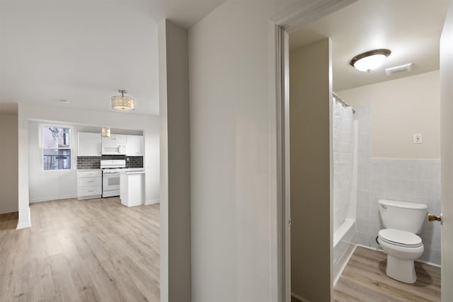 full bathroom featuring visible vents, tile walls, wood finished floors, toilet, and shower / bathtub combination with curtain