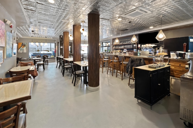 dining space featuring finished concrete floors, a dry bar, and an ornate ceiling