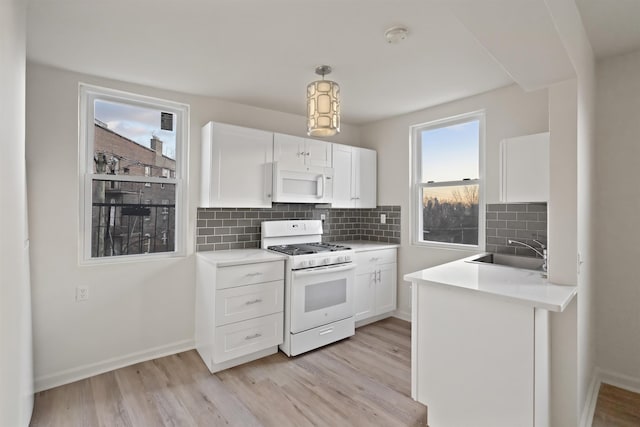 kitchen featuring a sink, light wood-style flooring, white appliances, and light countertops