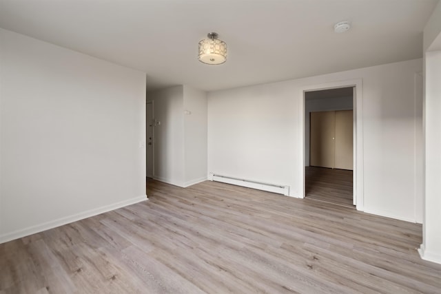 spare room with baseboards, baseboard heating, and light wood-style flooring