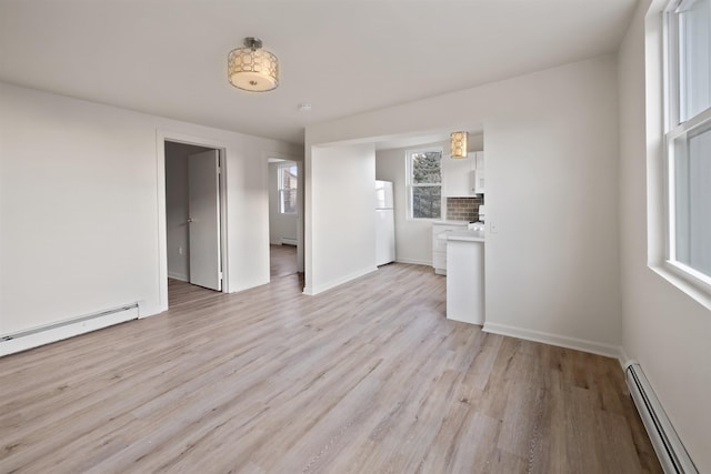 unfurnished living room with baseboards, a baseboard heating unit, light wood-style flooring, and a baseboard radiator