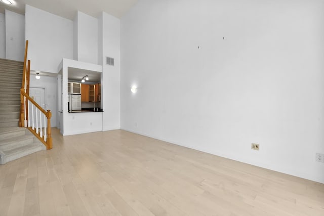 26 Ave At Port Imperial Unit 440, West New York, NJ 07093 - unfurnished living room with a towering ceiling, stairway, and light wood-style flooring
