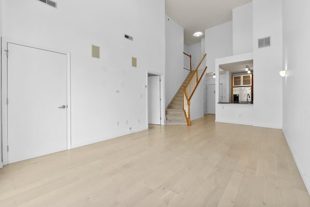 26 Ave At Port Imperial Unit 440, West New York, NJ 07093 - unfurnished living room with a towering ceiling, stairs, and light wood-style floors