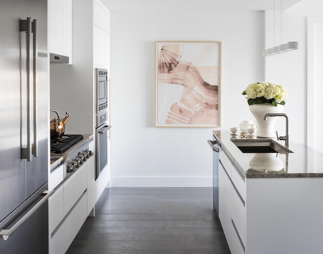 kitchen featuring modern cabinets, dark wood-style floors, white cabinets, a sink, and stainless steel appliances
