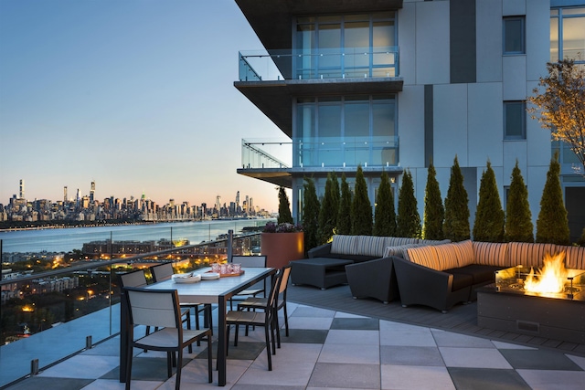 view of patio / terrace with an outdoor living space with a fire pit, outdoor dining area, a city view, and a balcony