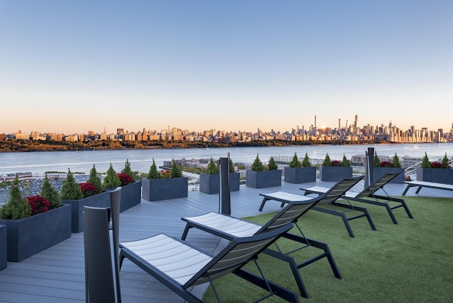 deck at dusk featuring a water view and a view of city