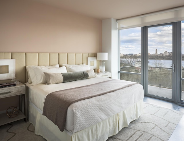bedroom with a water view, access to exterior, expansive windows, and light carpet