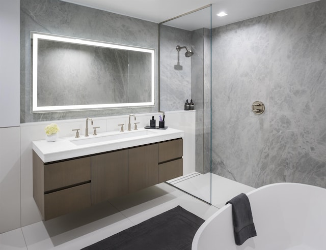 bathroom featuring vanity, a walk in shower, a freestanding bath, and tile walls
