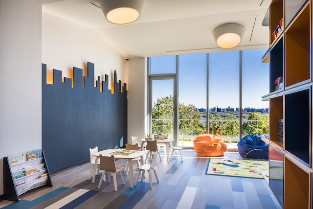 interior space with plenty of natural light, a view of city, wood finished floors, and a wall of windows
