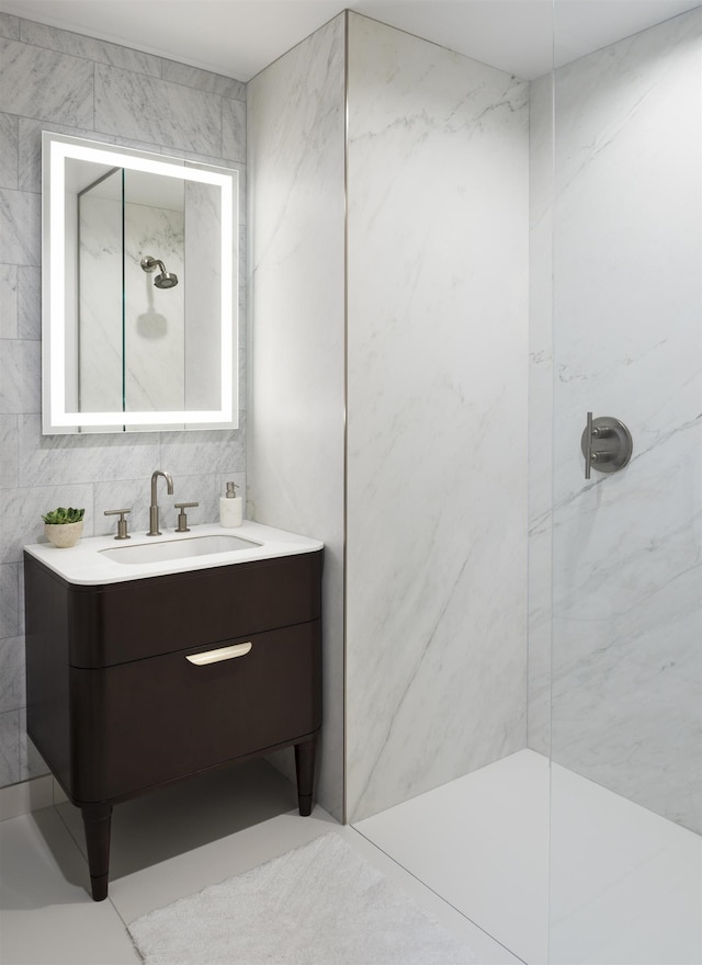 bathroom with vanity, a marble finish shower, and tile walls