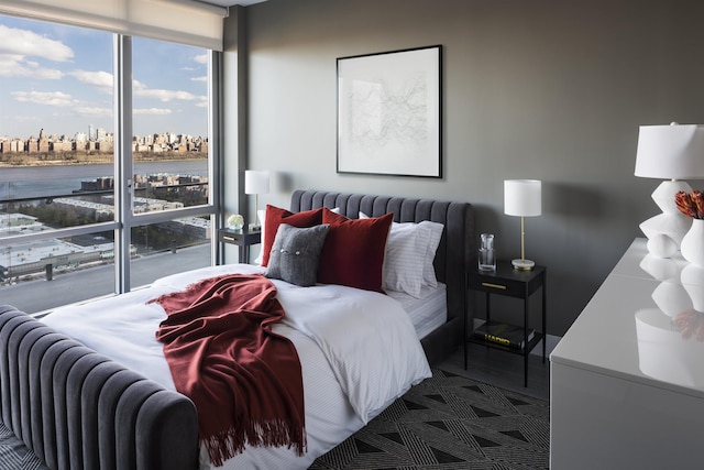 bedroom with a view of city, a water view, and floor to ceiling windows