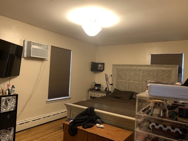 1518 38th St, North Bergen, NJ 07047 - bedroom featuring a baseboard radiator, an AC wall unit, and wood finished floors