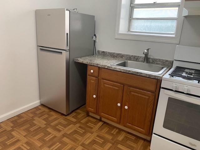 1518 38th St, North Bergen, NJ 07047 - kitchen with white gas range oven, freestanding refrigerator, a sink, brown cabinetry, and light countertops