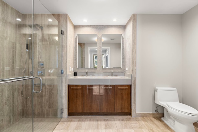 bathroom with a shower with door, vanity, and toilet