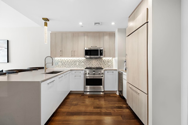 kitchen featuring sink, kitchen peninsula, dark hardwood / wood-style floors, high end appliances, and hanging light fixtures