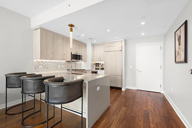 kitchen with sink, light brown cabinetry, backsplash, paneled fridge, and dark wood-type flooring